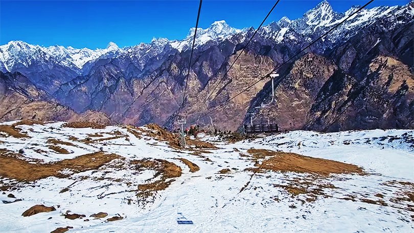 Tourists riding the Auli Chair Lift with sweeping views of snow-covered slopes in Auli Uttarakhand