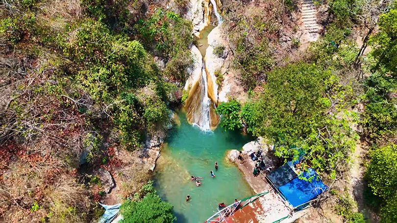 Crystal clear waters of Neer Garh Waterfall surrounded by lush green forest