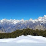 Panoramic view of snow-covered slopes, alpine meadows, and Nanda Devi from Auli, showcasing Auli Uttarakhand