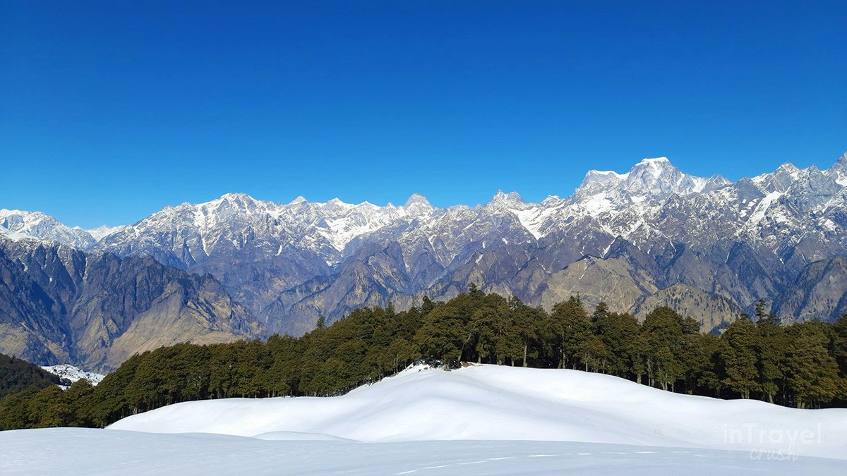 Panoramic view of snow-covered slopes, alpine meadows, and Nanda Devi from Auli, showcasing Auli Uttarakhand