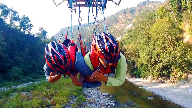 Tourist gliding over the Ganga valley on a flying fox zip line adventure