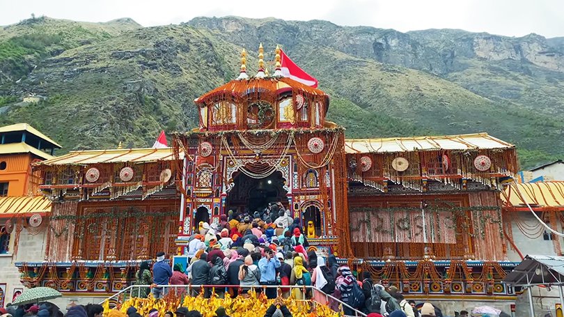 Badrinath Dham temple with colorful facade and devotees, highlight of Char Dham Yatra 2025.