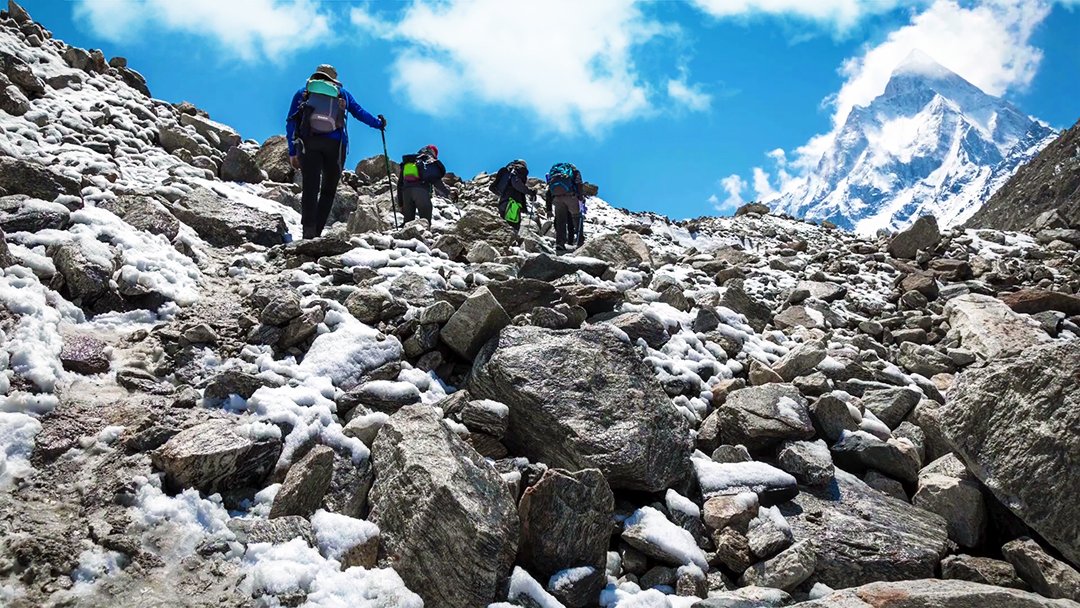 Group of trekkers climbing steep rocky mountain trail towards Tapovan, stunning backdrop of Shivling peak, adventure highlight of the Gaumukh Tapovan trek guide.