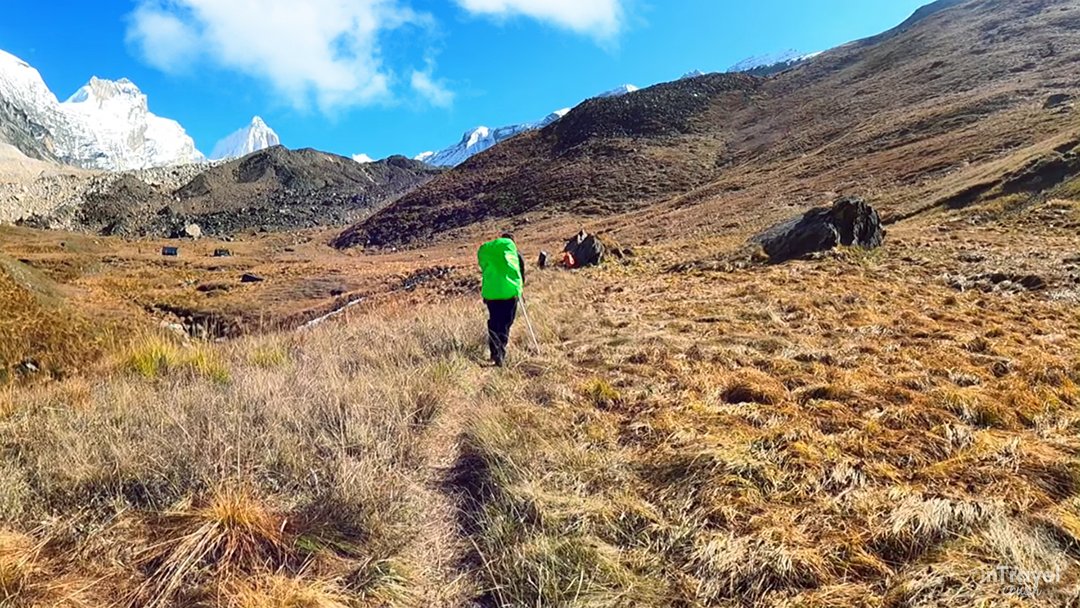 Trekkers hiking from Bhoj Kharak to Kedar Kharak on Kedar Tal Trek Guide 2026, with snow-capped Himalayan peaks and lush alpine meadows in view.