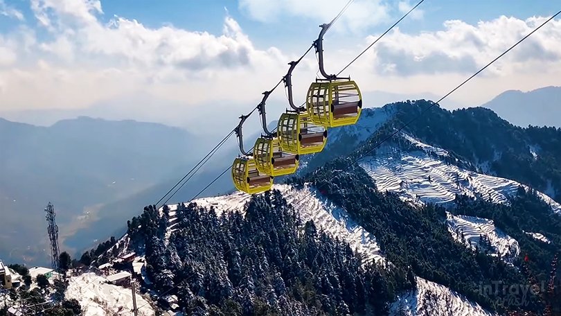 Dhanaulti Eco Park winter view with snow-covered ground, tall deodar trees, ropeway to Surkanda Devi Temple, and quiet surroundings.