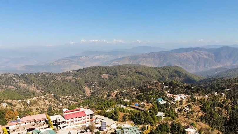 View of Mukteshwar town with snow-covered Himalayan peaks in the background.