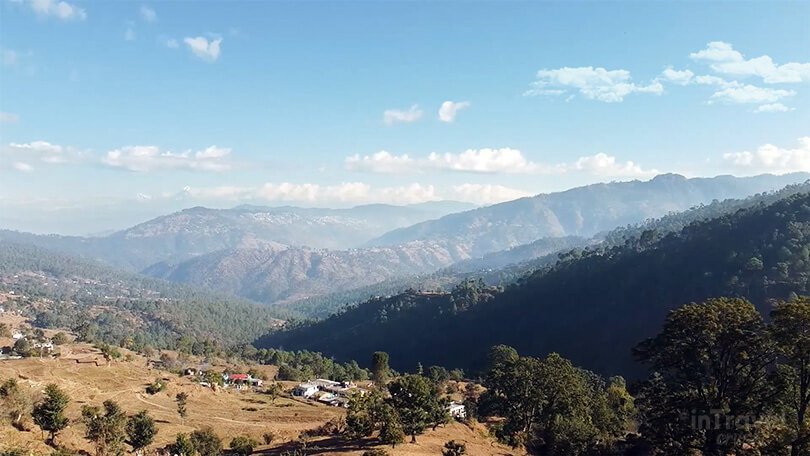 Peora Eco Village showing traditional Kumaoni houses, terraced fields and mountain scenery.